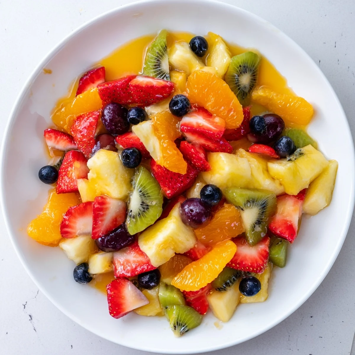 A bright bowl of fruit salad, featuring strawberries, kiwi, and grapes, chilled and ready to serve.