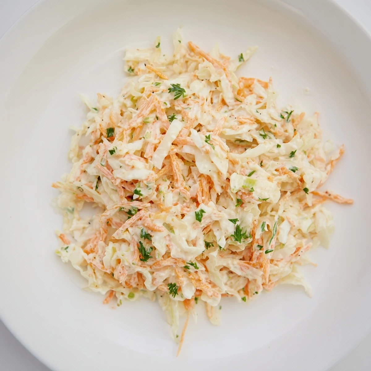 Freshly made coleslaw with apple features shredded cabbage and grated apple, ready to eat.
