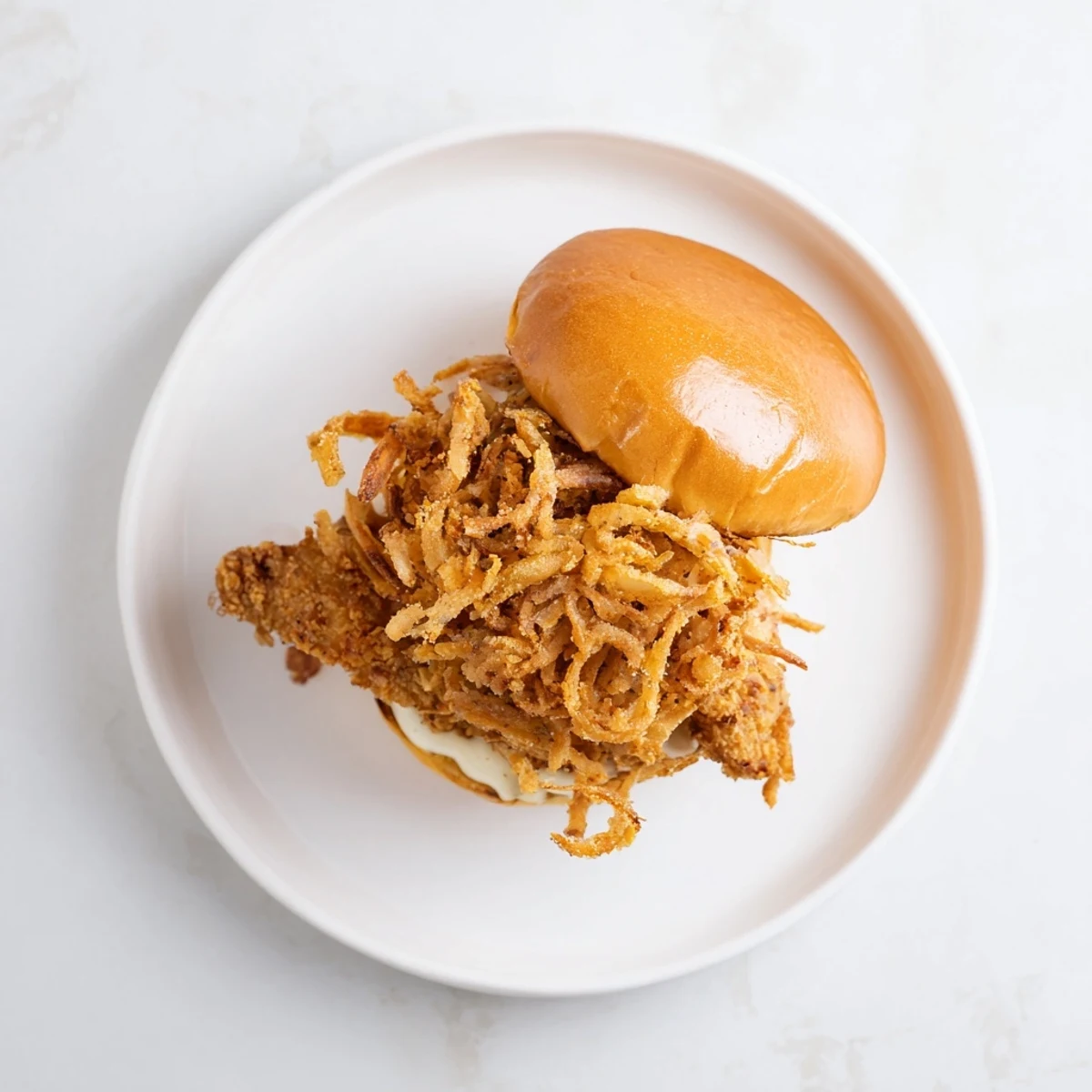 Golden fried chicken thighs with crispy onions on a toasted brioche bun with creamy aioli.  