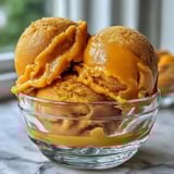 Silky-smooth mango sorbet with a vibrant golden hue, bursting with tropical sweetness and a zesty lime finish.  