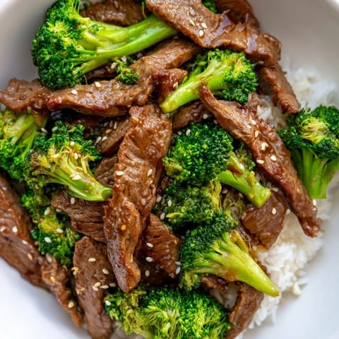 A steaming plate of Beef and Broccoli, featuring savory beef and vibrant green broccoli in sauce.