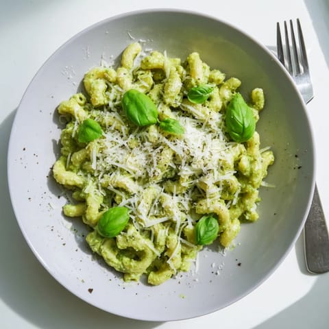 Serving suggestion for creamy avocado pesto mac, garnished with basil and pepper, ready to enjoy warm and fresh.