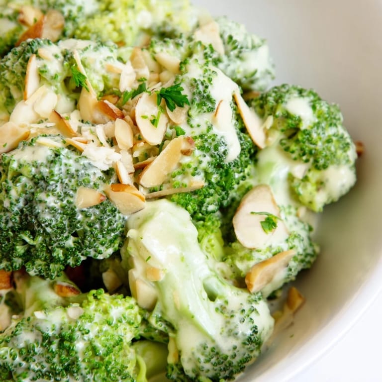 Chilled Garlic Parmesan Broccoli Salad served with grilled chicken, showcasing a creamy, garlicky dressing and crunchy toasted almonds for a light lunch.