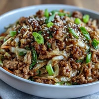 A savory keto egg roll in a bowl with ground turkey, crisp cabbage, and sesame oil in a sizzling skillet.