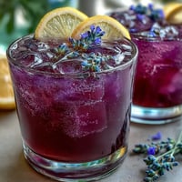 Purple Rain Lavender Lemonade Refresher with fresh citrus and floral lavender notes, served over ice with lemon slices and lavender sprigs.